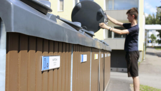 Nuori mies laittaa roskapussia jätteenkeräysastiaan.